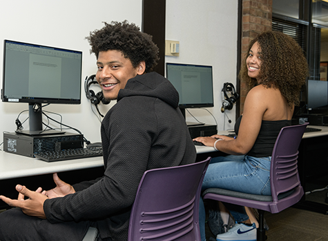 Two Black students smiling at computers
